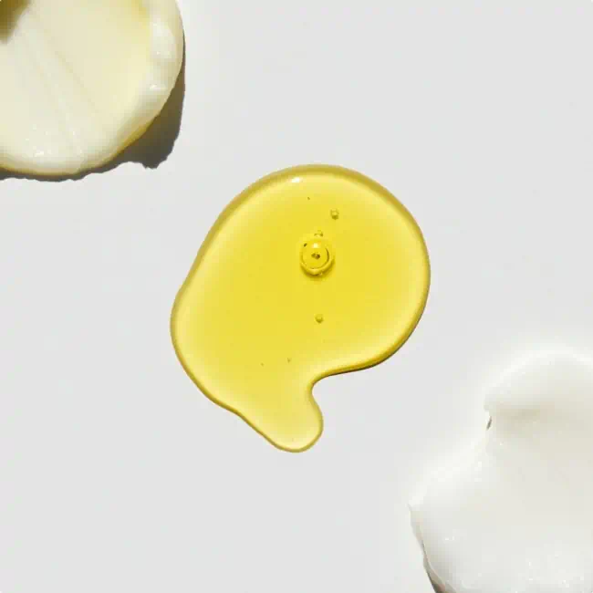 Swatch of yellow avocado oil and creamy skincare products on a white surface