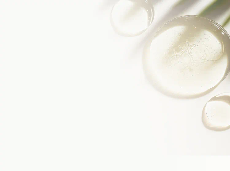 Clear glycerin drops on a white surface with soft shadows