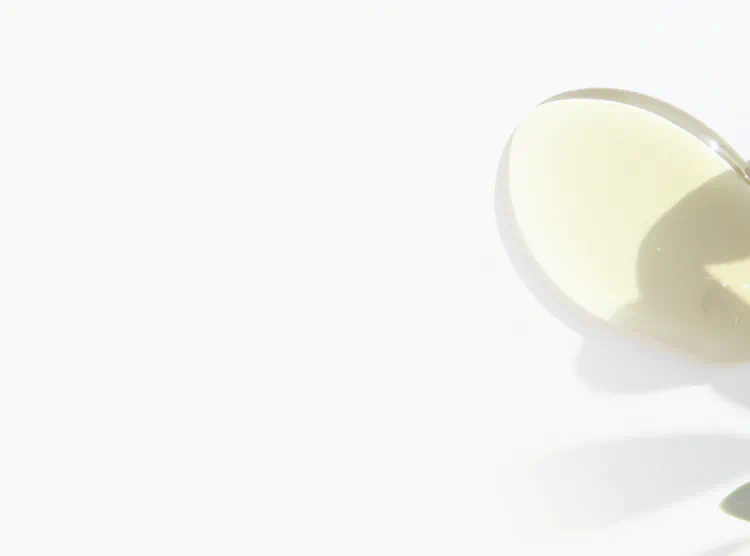 Golden drop of Vitamin E oil on a white surface